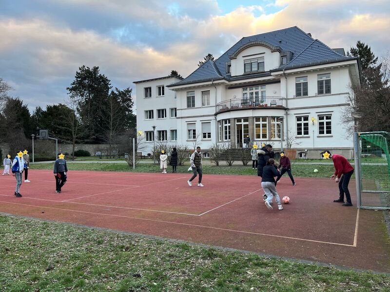 Das soziale Engagement der Kaiser Friedrich Pharma GmbH mit Unterstützung der Stiftung Waisenhaus Frankfurt und Foto eines Fußballplatzes vor dem Gebäude der Stiftung mit spielenden Kindern